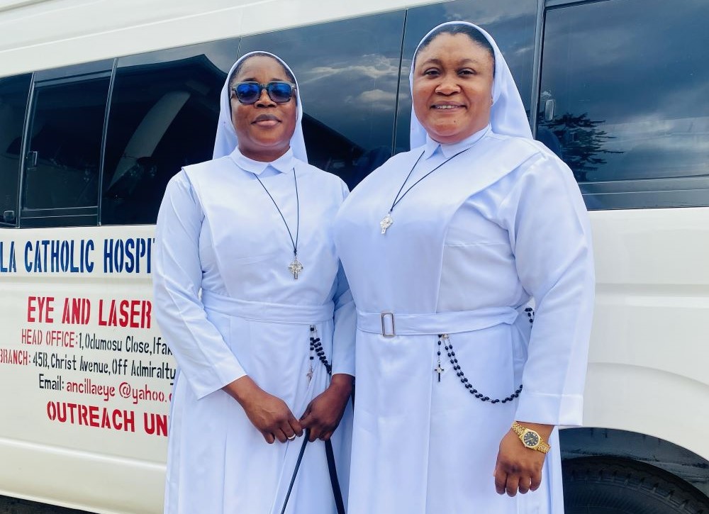 Sr. Maryann Ononiwu, administrator of Ancilla Catholic Hospital in Lagos, Nigeria; and Sr. Mary Elizabeth Adedeji, the hospital's pharmacist and antiretroviral therapy coordinator, pose in front of one of the hospital's buses at their convent west of Lagos. (Valentine Benjamin)