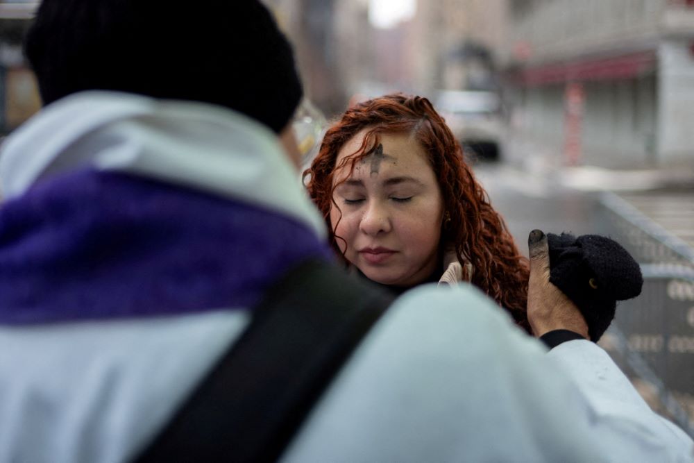 Fr. Fabian Arias marks a cross with ashes on the forehead of a woman outside a U.S. immigration court in the Manhattan borough of New York City Feb. 18. (OSV News/Reuters/David 'Dee' Delgado)