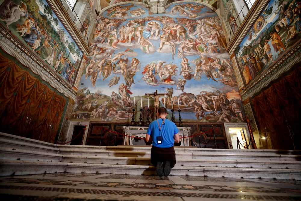 A visitor kneels in front of "The Last Judgement" fresco by the Italian Renaissance painter Michelangelo inside the Sistine Chapel in Rome, May 3, 2021. (AP/Alessandra Tarantino, file)