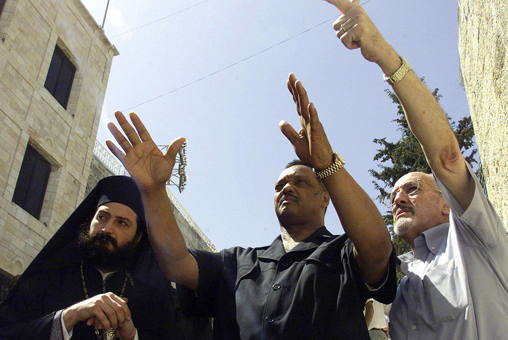U.S. activist the Rev. Jesse Jackson (center) tours the area surrounding Bethlehem's Church of the Nativity in the West Bank July 30, 2002. Jackson called on then-President George W. Bush to help bring reconciliation between Israelis and Palestinians. (CNS/Reuters)