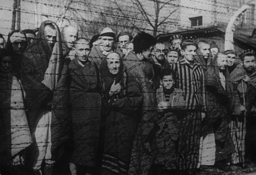 Men, women and children are seen behind barbed wire after the liberation of the Auschwitz-Birkenau Nazi death camp in 1945 in Oswiecim, Poland. Historians estimate that the Nazis sent at least 1.3 million people to Auschwitz between 1940 and 1945, and it is believed that some 1.1 million of those perished there. Auschwitz was liberated by the Russian Army Jan. 27, 1945. (OSV News/Reuters/Yad Vashem Archives)