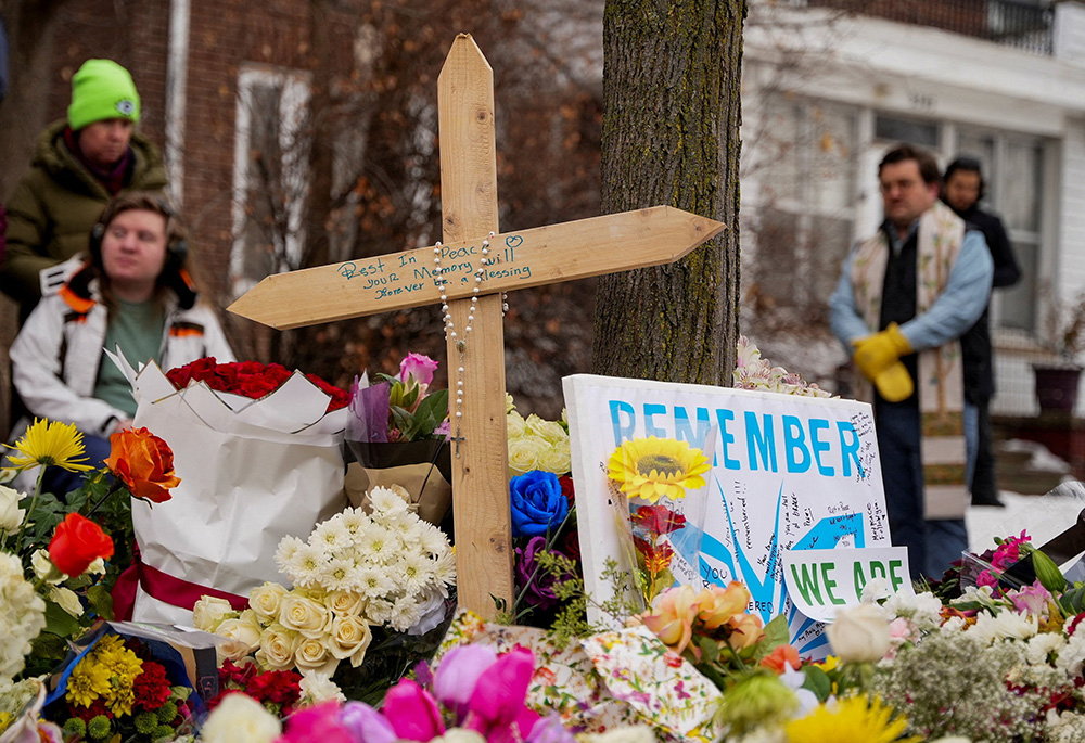 A rosary is draped over a cross as people gather by a makeshift memorial in Minneapolis Jan. 8, 2026, at the scene of the fatal shooting of Renee Nicole Good by a U.S. Immigration and Customs Enforcement agent. (OSV News/Reuters/Tim Evans)