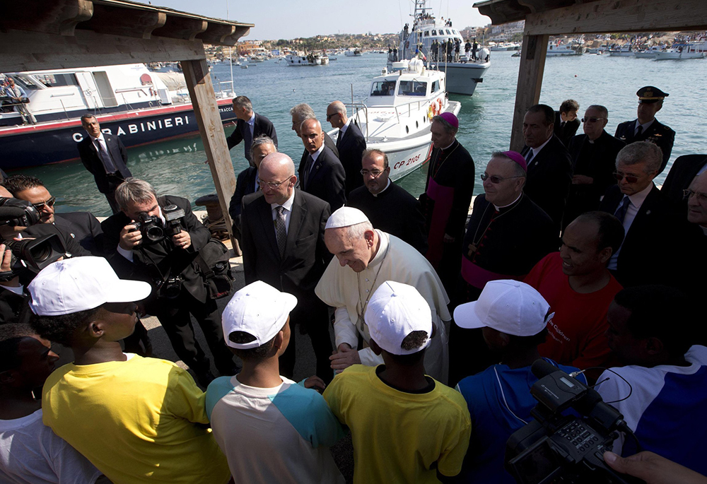 Pope Francis talks with immigrants at the port in Lampedusa, Italy, July 8, 2013. Two months after his election, the late pope visited the tiny Italian island in the Mediterranean Sea to draw attention to those who had lost their lives attempting the crossing from the African coast. On Feb. 19, 2026, the Vatican announced that Lampedusa will be one of six destinations for upcoming day trips Pope Leo XIV will make. (CNS/pool via Reuters)