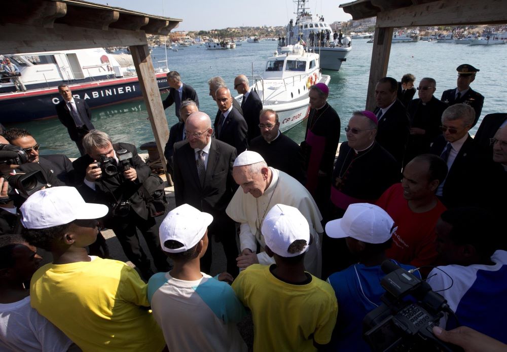 Pope Francis talks with immigrants at the port in Lampedusa, Italy, July 8, 2013. Two months after his election, the late pope visited the tiny Italian island in the Mediterranean Sea to draw attention to those who had lost their lives attempting the crossing from the African coast. (CNS/pool via Reuters)