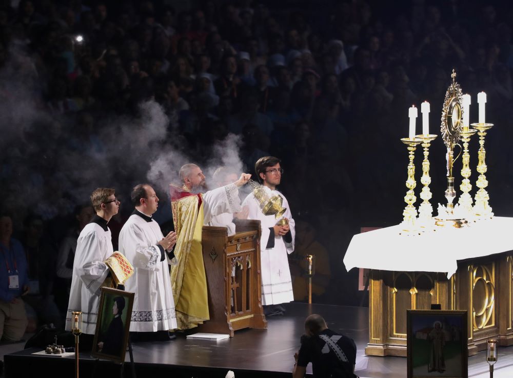Fr. Boniface Hicks, a Benedictine monk of St. Vincent Archabbey in Latrobe, Pa., swings a censer in front of the monstrance during eucharistic adoration July 19, 2024, at the third revival night of the National Eucharistic Congress at Lucas Oil Stadium in Indianapolis. (OSV News/Bob Roller)