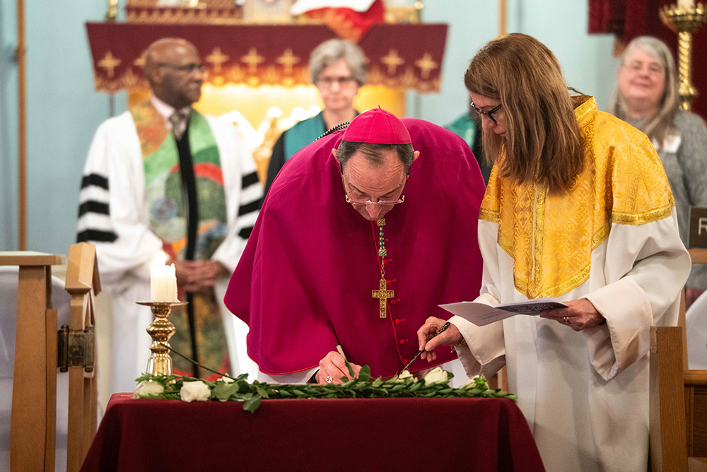 Auxiliary Bishop Mark Bartosic signs on behalf of the Chicago Archdiocese two Christian-organized letters — calling on lawmakers to rapidly replace lead pipes in Illinois and to reenter the Paris Agreement on climate change — during a Jan. 24, 2026, ecumenical prayer service at St. Gregory the Illuminator Armenian Apostolic Church in Chicago. (Deb Winarski)