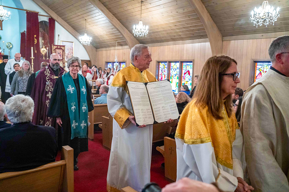 Geroge Nassos, a member of the Greek Orthodox Church, carries two letters from Chicagoland Christian leaders calling for environmental actions during a Prayer Service Jan. 24, 2026, during the Week of Prayer of Christian Unity at St. Gregory the Illuminator Armenian Apostolic Church in Chicago. (Deb Winarski)
