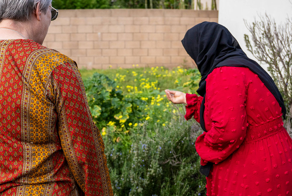 A woman staying in the CSJ Shelter for Refugee Families, a ministry that sponsors and houses families in the immigration process, shows St. Joseph Sr. Sue Dunning, left, the plants in the shelter's garden. (Courtesy of the Sisters of St. Joseph of Orange)