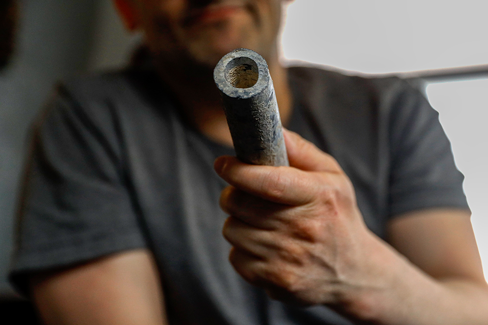 Troy Hernandez, an environmental justice activist with Pilsen Environmental Rights and Reform Organization shows a piece of lead pipe obtained from his residence during his home renovation, April 9, 2021, in Chicago's Pilsen neighborhood. (AP/Shafkat Anowar)