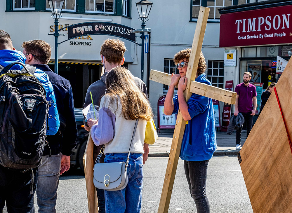 A young man carries a cross as he participates in a Good Friday service in Epsom, Surrey, England, April 15, 2022. (Dreamstime/Martinlee58)