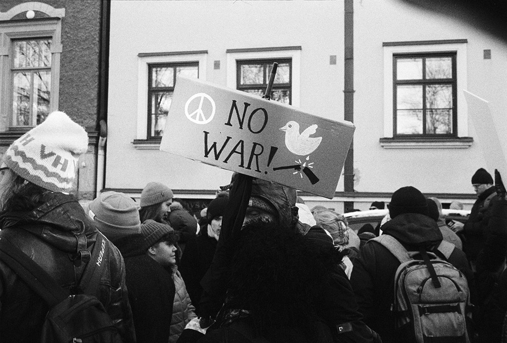 Person holding a sign that says, "NO WAR!" (Unsplash/ench)