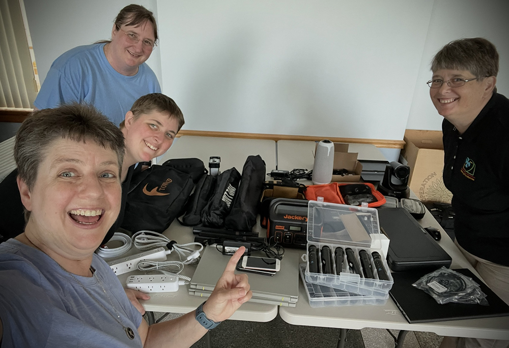 Benedictine Tech Ministries team members pose for a picture: from left are Sr. Michelle Sinkhorn, Sr. Raphaela Cady, Sr. Tamra Thomas, and Sr. Stefanie Macdonald "We have microphones and speakers, a projector and screen, two laptops, five cameras, power strips, etc. — everything we need so we can go anywhere, as long as they have internet and run all the technology for a hybrid or in-person only conference," Sinkhorn said. (Courtesy of Benedictine Tech Ministries)