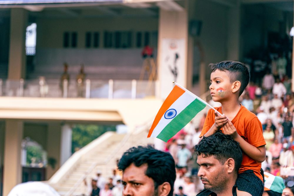 A child on a man's shoulders holds an Indian flag in Attari, Punjab, India, Feb. 13, 2025. (Unsplash/Raju Kumar)