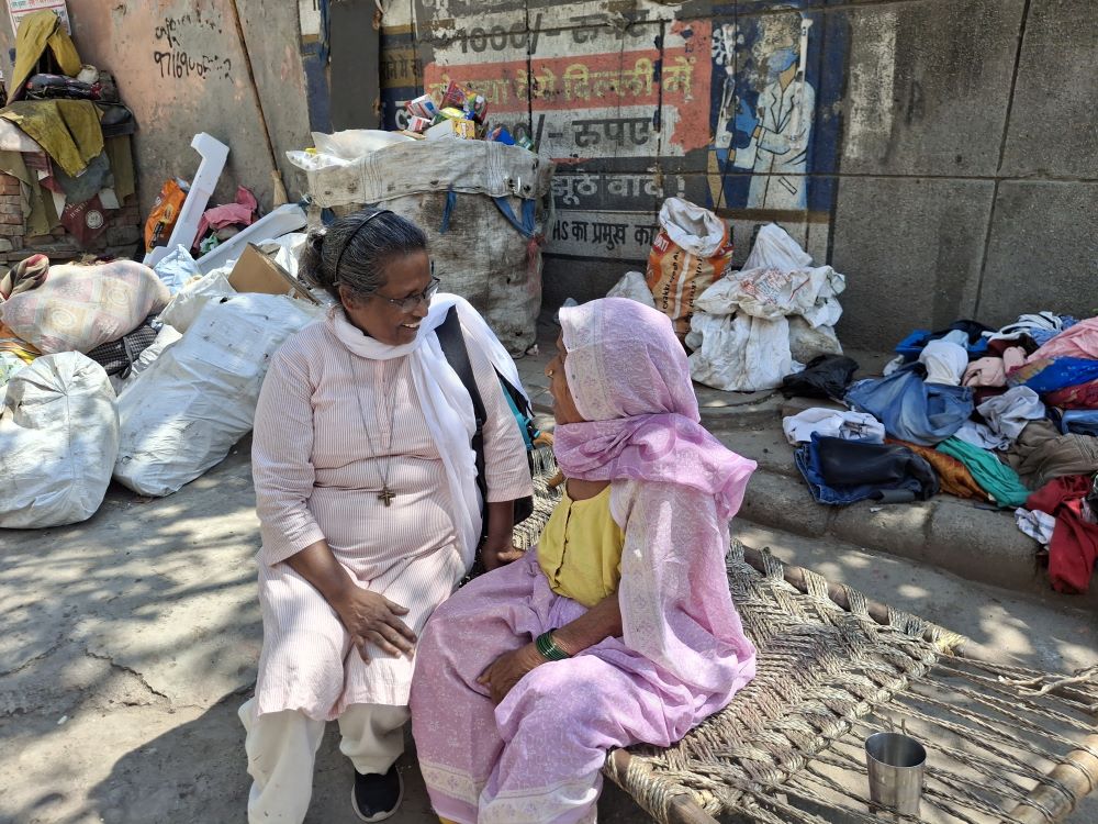 Sr. Connie Callista, a member of the Holy Cross Sisters of Chavanod, sits with an elderly woman at Trilokpuri, an enclave in East Delhi. (Lissy Maruthanakuzhy)