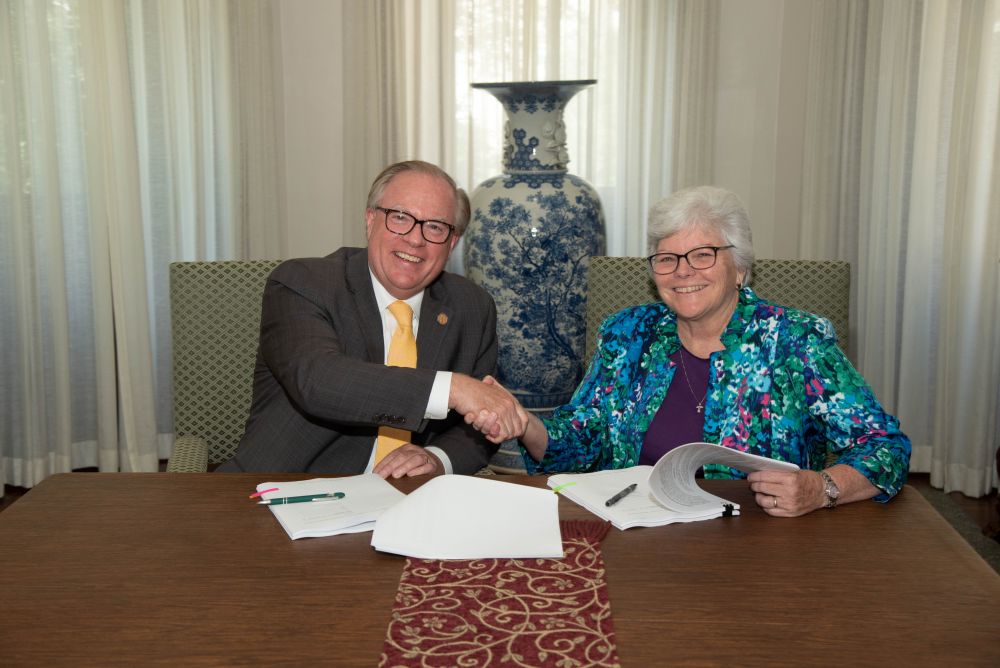 Neumann University President Chris Domes and Sr. Kathy Dougherty sign papers in June 2021 transferring ownership of the Sisters of St. Francis of Philadelphia's motherhouse, other buildings and 63 acres to the university. (Courtesy of the Sisters of St. Francis of Philadelphia)