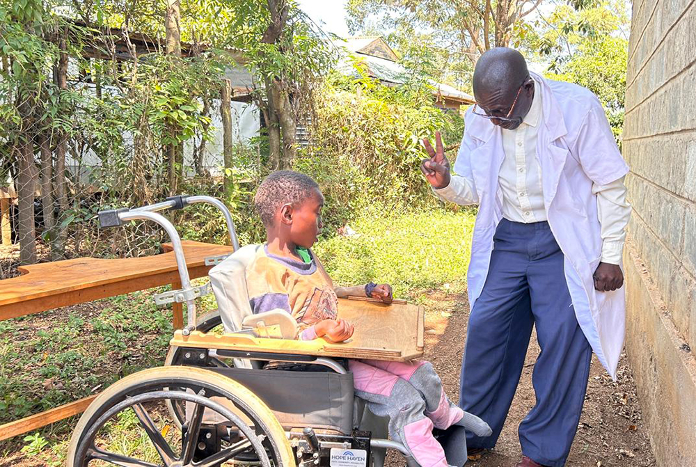 Christopher Onyango, a teacher at Sigomere Small Home, with a child during a lesson in Siaya County, western Kenya. Staff focus on building practical skills and celebrating small milestones. (GSR photo/Doreen Ajiambo)