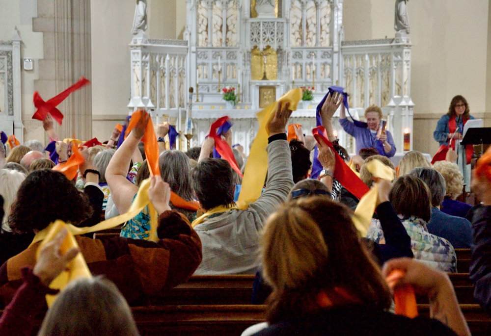 Attendees at the Women's Ordination Conference's 50th anniversary celebration wave multi-colored stoles May 22, 2026, in Detroit. (GSR photo/Dan Stockman)