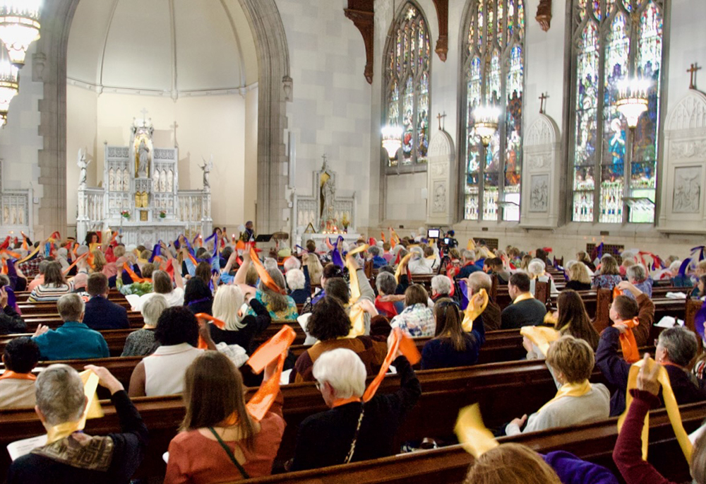 Attendees at the Women's Ordination Conference's 50th anniversary celebration wave multi-colored stoles May 22, 2026, in Detroit. (GSR photo/Dan Stockman)
