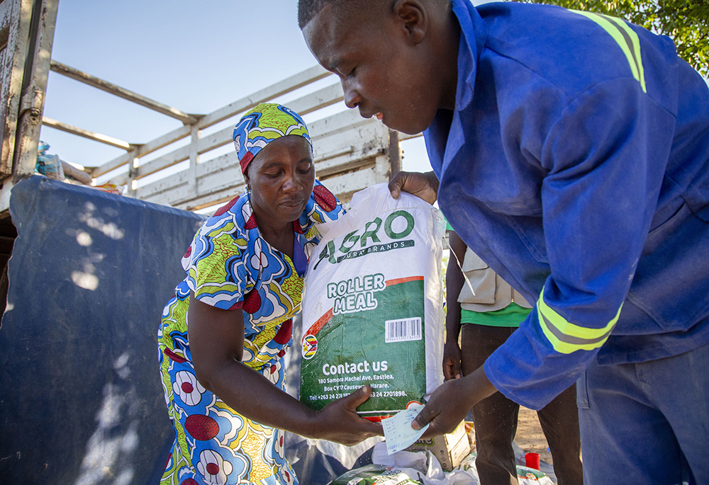 A community member receives food after redeeming her voucher at a distribution center in the village of Masera, Zimbabwe, Dec. 2, 2024. (OSV News/Catholic Relief Services/Dooshima Tsee)