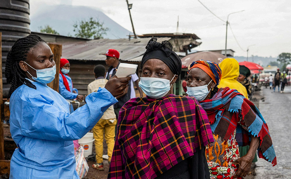 A health worker takes the temperature of a woman passing through the Kanyaruchinya checkpoint into the city of Goma, Congo May 20, 2026, as authorities and aid agencies intensify efforts to contain a new Ebola outbreak caused by the Bundibugyo strain. (OSV News/Reuters/Arlette Bashizi)