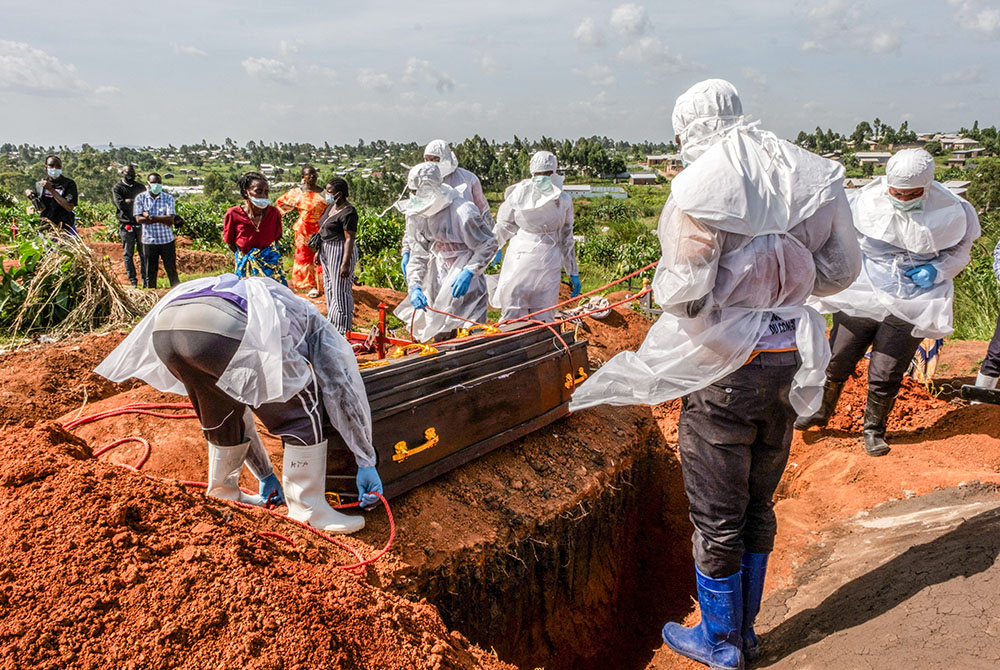 Red Cross workers wearing personal protective equipment at the Nyamurongo cemetery in Bunia, Congo, May 26, 2026, prepare to bury a coffin containing the body of Dr. Tibenderana Katho Blaise, who worked at the Center Medical Evangelique in Hoho commune and died of Ebola virus. (OSV News/Reuters)