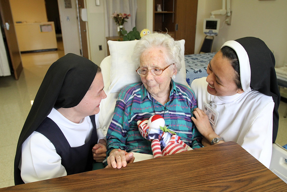 A file photo shows Dominican postulant Anna Harper and Dominican Sr. Carmela Marie visit with patient Edna MacCready at Rosary Hill Home in Hawthorne, N.Y. (OSV News/Gregory A. Shemitz)