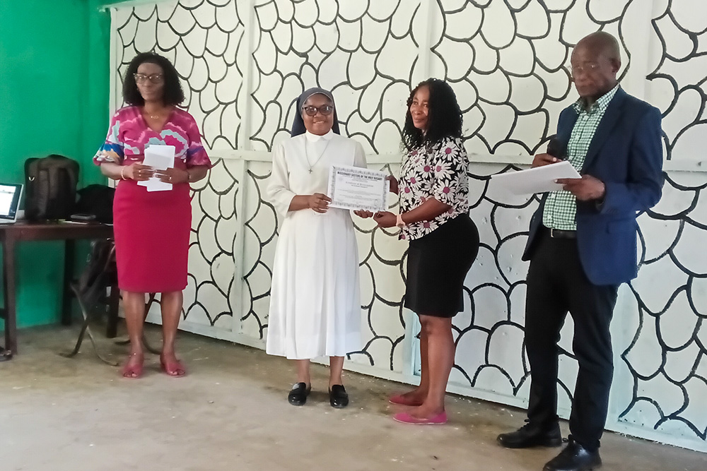 Sr. Onyinyechukwu Bernadette Ezejesi of the Missionary Sisters of Our Lady of the Holy Rosary presents certificates of participation to teachers trained in child-centered learning and child safeguarding Oct. 21, 2025, at St. Helena's Secondary School, Dockyard Community, Freetown, Sierra Leone. (Courtesy of Misean Cara Ireland/NLW Germany)