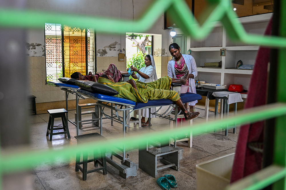 Sr. Sujatha Kattula, left, a Missionary Sister of the Immaculate, and nurse Martha Murmu dress a patient's wounds. The facility provides institutional treatment for those with severe conditions. (Piyas Biswas)