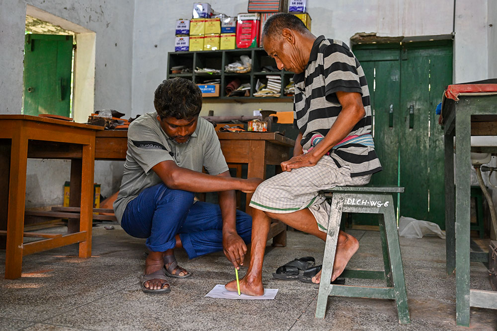 A footwear technician takes measurements to craft custom shoes. This specialized footwear is vital for protecting insensitive feet from further trauma and ulceration. (Piyas Biswas)