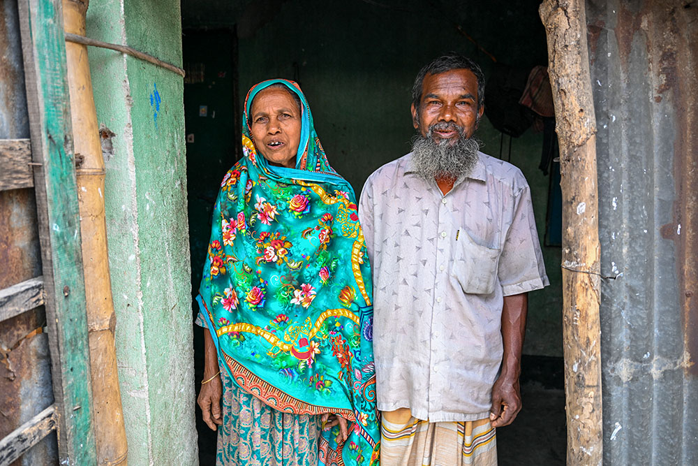 Mohmmad Montu Sarkar, 63, poses with his wife in front of his home. After a year of treatment at the center, Sarkar was able to return to his family and lead a normal life. (Piyas Biswas)