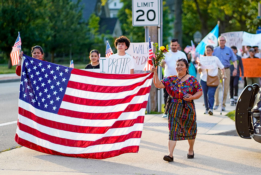 Women hold a U.S. flag as they lead a pro-immigrant march following a Spanish-language Mass at St. John the Evangelist Church in Riverhead, N.Y., June 22, 2025, the feast of the Body and Blood of Christ. (OSV News/Gregory A. Shemitz)