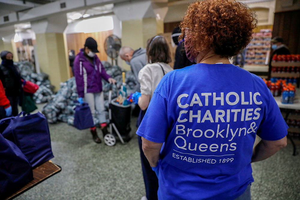 A volunteer in New York City looks on as people receive free food at a food pantry for needy residents run by Catholic Charities Brooklyn and Queens April 24, 2020. (OSV News/Reuters/Mike Segar)