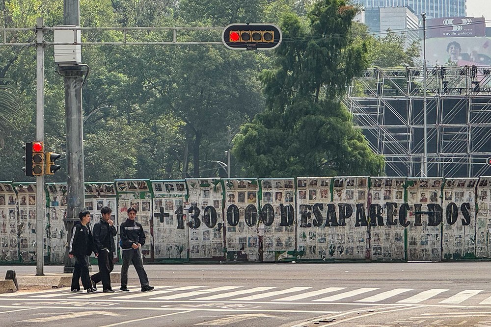 Un grupo cruza el Paseo de la Reforma en Ciudad de México, el 6 de julio de 2026, junto a cientos de fotos de mujeres, hombres y niños desaparecidos adosadas a una pared, para visibilizar la crisis de más de 130 000 desaparecidos en México, aprovechando la atención internacional del Mundial de la FIFA 2026. (Foto: GSR en español/Rhina Guidos)