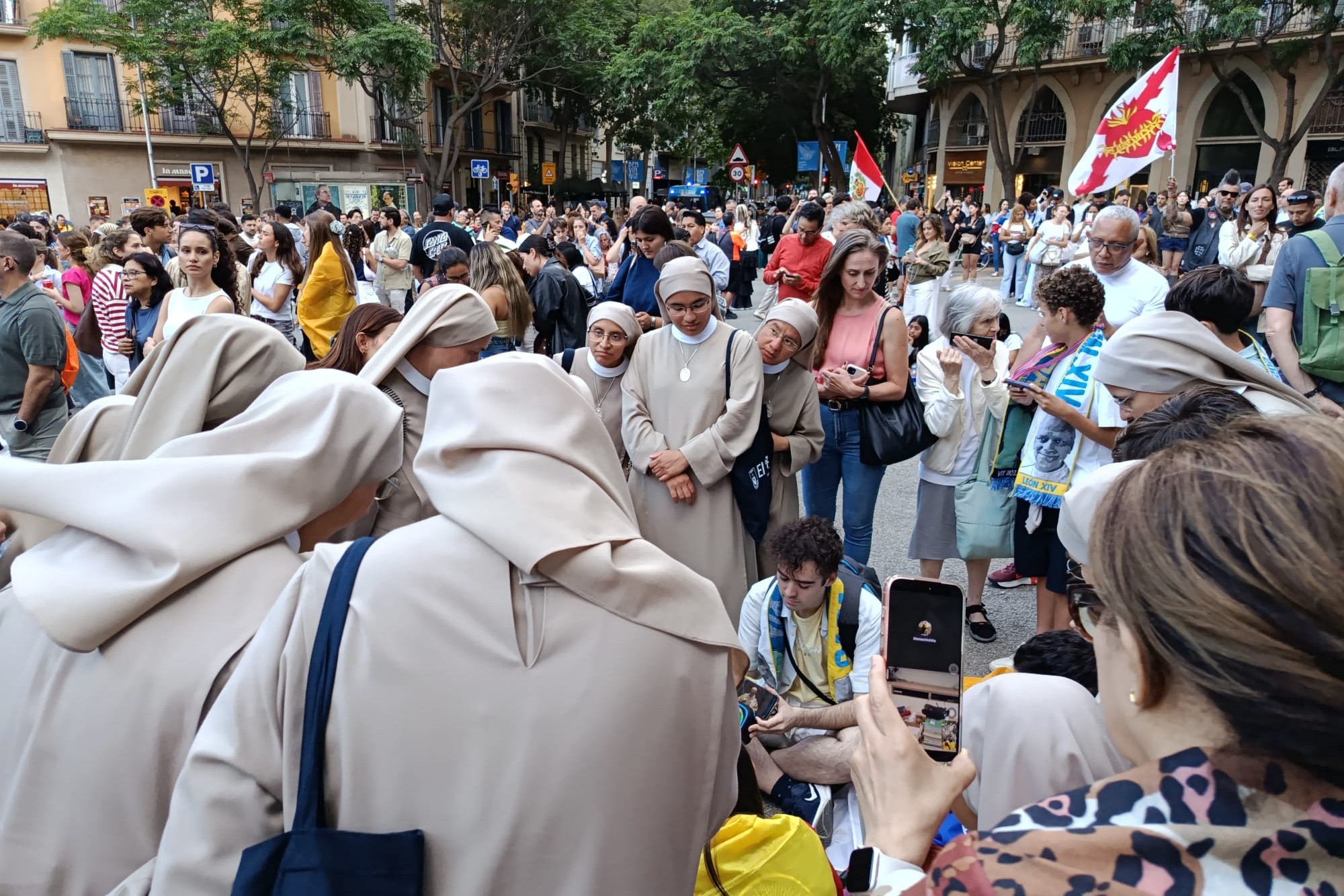 Un grupo de religiosas sigue la eucaristía papal a través de un teléfono móvil en la puerta de la Sagrada Familia de Barcelona. (Foto: Miguel Ángel Malavia)