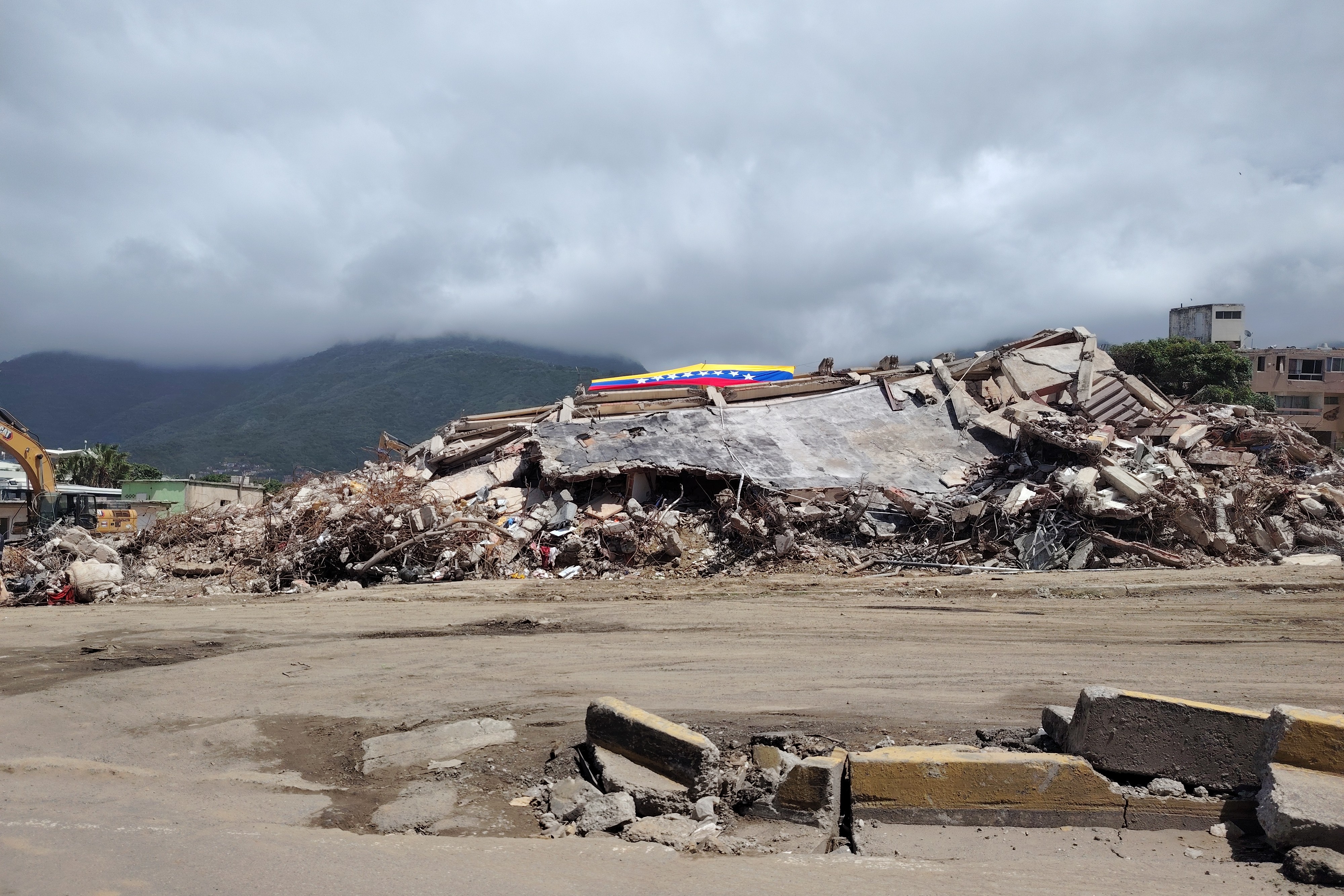 Una bandera ondea sobre los escombros de un edificio colapsado en el sector El Caribe, una de las zonas más afectadas del estado La Guaira. 19 de julio de 2026. (Foto: Graciela Portillo)