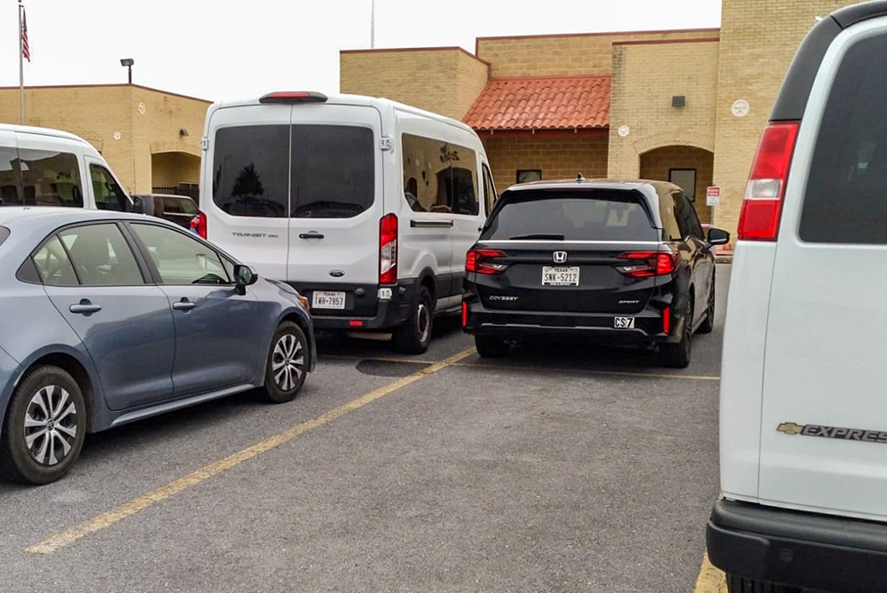 White vans parked outside the immigration courts in Harlingen, Texas, means there are unaccompanied minors with immigration hearings that day. The children travel in the vans from shelters where they stay until they can be placed with relatives or a guardian, or be deported. (Courtesy of Rose Kuhn)