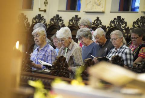 The sisters in choir rows, praying from books. 