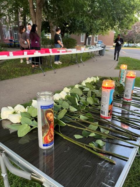 Candles and white roses honor victims at vigil.