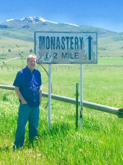 Mike O'Brien stands near roadside sign to monastery.