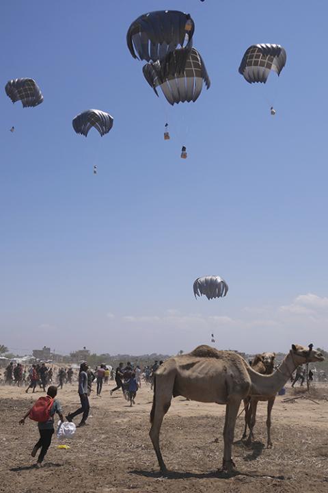 Palestinians rush to collect humanitarian aid airdropped by parachutes into Zawaida in the central Gaza Strip, Aug. 4, 2025. (AP Photo/Abdel Kareem Hana)