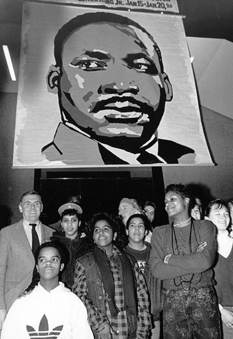 In 1986, Boston Mayor Raymond Flynn, left, poses for a photo with young people underneath a portrait of the Rev. Martin Luther King Jr. (Wikimedia Commons/City of Boston Archives)