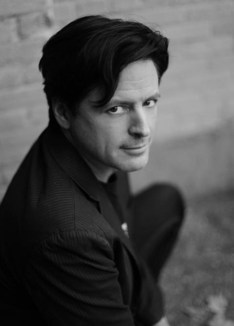 A black-and-white photo of John Fugelsang, looking up at the camera facing right at an angle.
