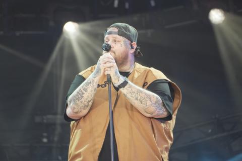 Jelly Roll performs live on stage at the Global Citizen Festival on Sept. 28, 2024. The artist is on stage ready to sing, holding both arms with microphones, engaging the audience with his energetic performance.