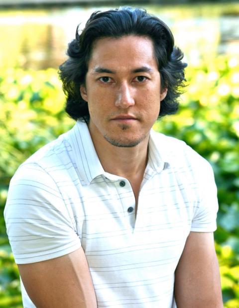 Paul Chappell sits positioned to the right and turns to face the camera. He has dark hair, tan skin and is wearing a white polo shirt.