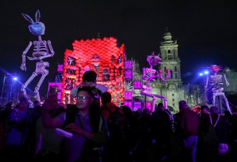 A man takes a selfie next to other people gathering near art installations of skeletons and other decorations at Zocalo Square in Mexico City Oct. 30, 2024, the eve of the Day of the Dead. The Metropolitan Cathedral is seen in the background. (OSV News/Reuters/Henry Romero)