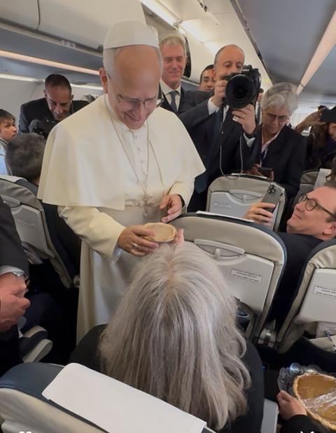 Pope Leo XIV receives a mini pumpkin pie from Cindy Wooden, editor-in-chief of Catholic News Service, during his Thanksgiving flight Nov. 27, 2025, to Turkey. Elise Allen, senior correspondent of Crux, prepares to hand the pope a full pie. (CNS/Claudio Lavanga)