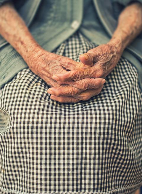 An older person sits with their hands folded, in shallow focus. (Unsplash/Danie Franco)