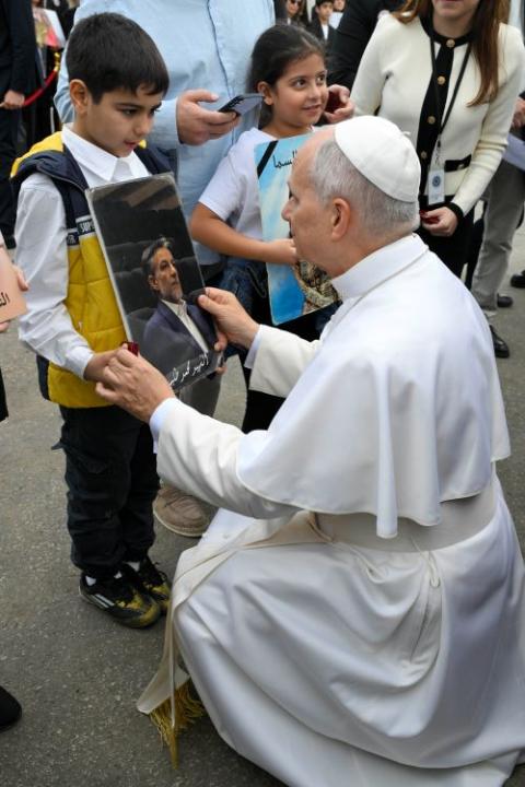 Pope Leo XIV kneels to speak to a boy in Beirut Dec. 2.