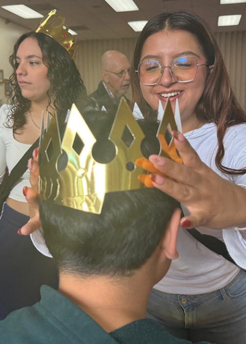 A nursing student volunteer helps a young boy try on his golden crown during a Three Kings Day celebration organized by the advocacy group Salvavision in Tucson, Arizona,  Jan. 4, 2026. (Anita Snow)