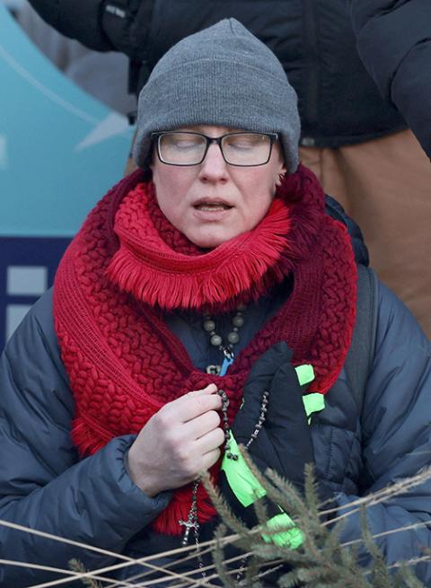 A woman prays with a rosary as people gather around a makeshift memorial in Minneapolis Jan. 25, 2026, at the site where Alex Pretti, 37,  was fatally shot by federal agents trying to detain him. (OSV News/Reuters/Evelyn Hockstein)
